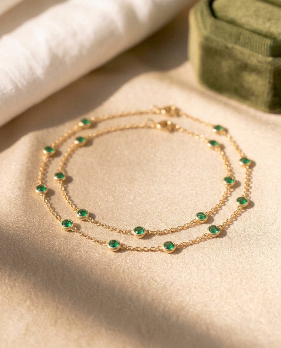 A long gold double-wrap chain scattered with small emeralds
