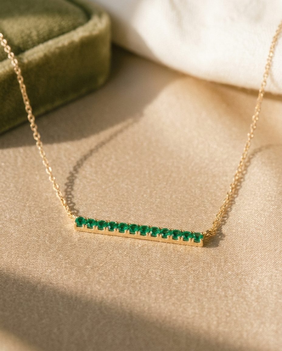 A gold chain with a horizontal bar set with small emeralds